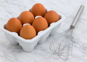 Carton of eggs and a whisk
