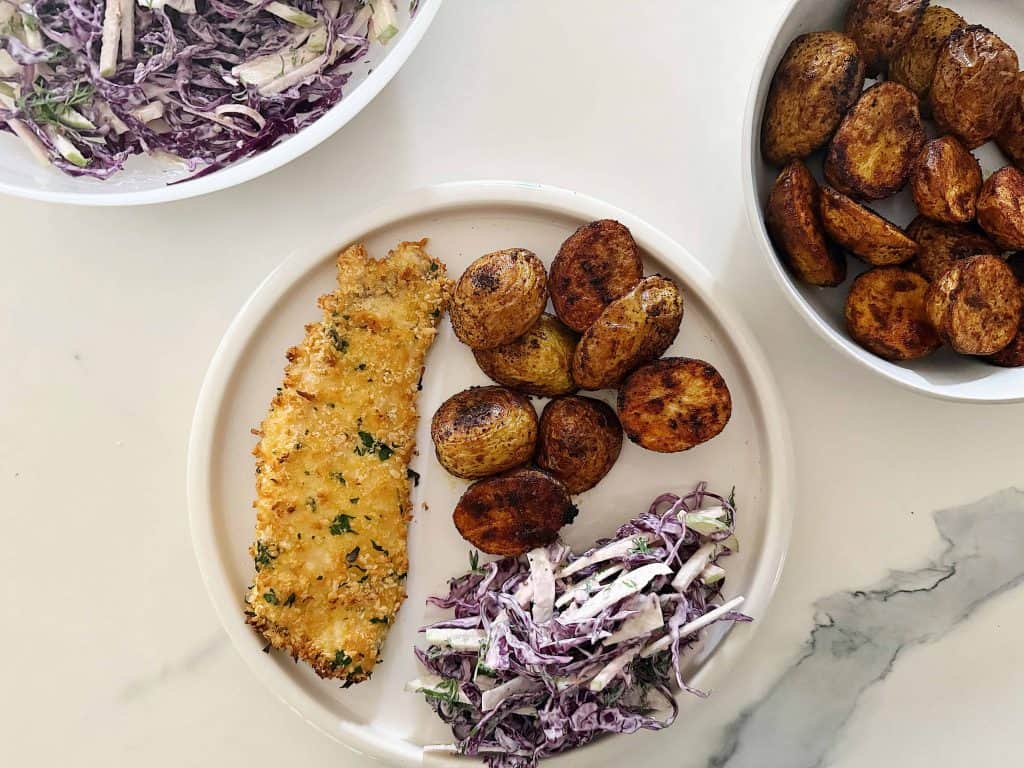Baked parmesan snapper schnitzel paired with slaw and roast potatoes
